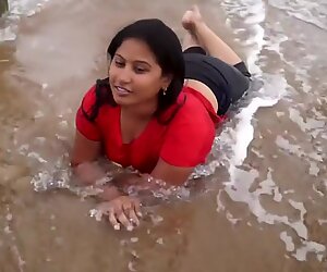 热辣的女孩潮湿在沙海滩上的表演和浪漫